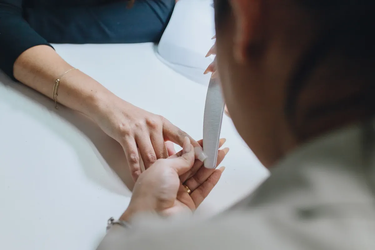 Close-up of a manicurist filing nails during a professional manicure session in a salon.
